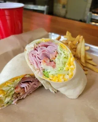 Cut wrap, filled with meat, lettuce, tomato, and french fries.