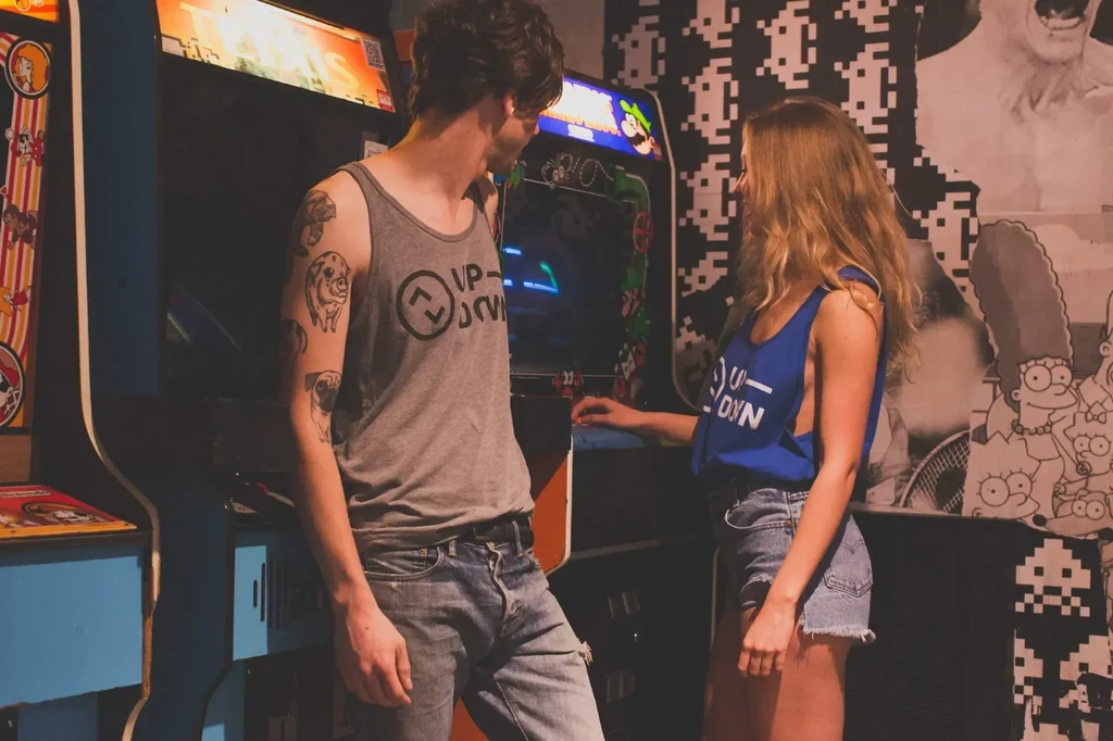 Man and woman looking at each other in a retro arcade bar.