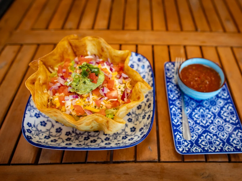 Crispy tortilla bowl filled with taco salad, guacamole, and salsa.