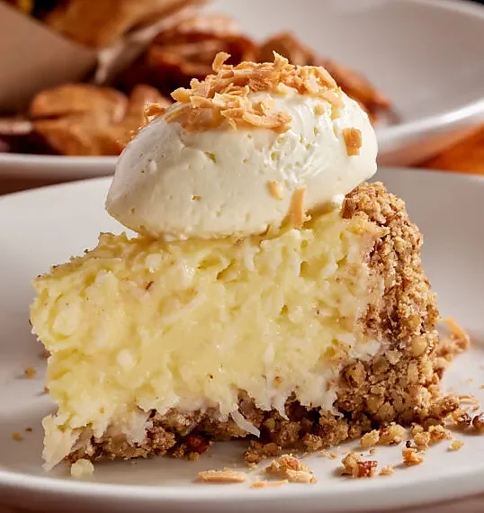 Slice of coconut cream pie with whipped cream and toasted coconut