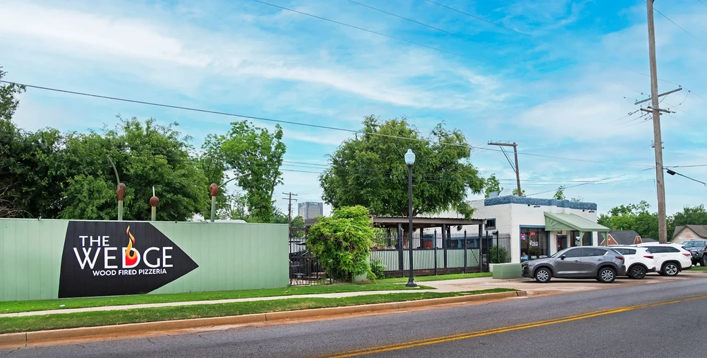 Exterior of The Wedge Wood Fired Pizzeria building, sign, and patio.