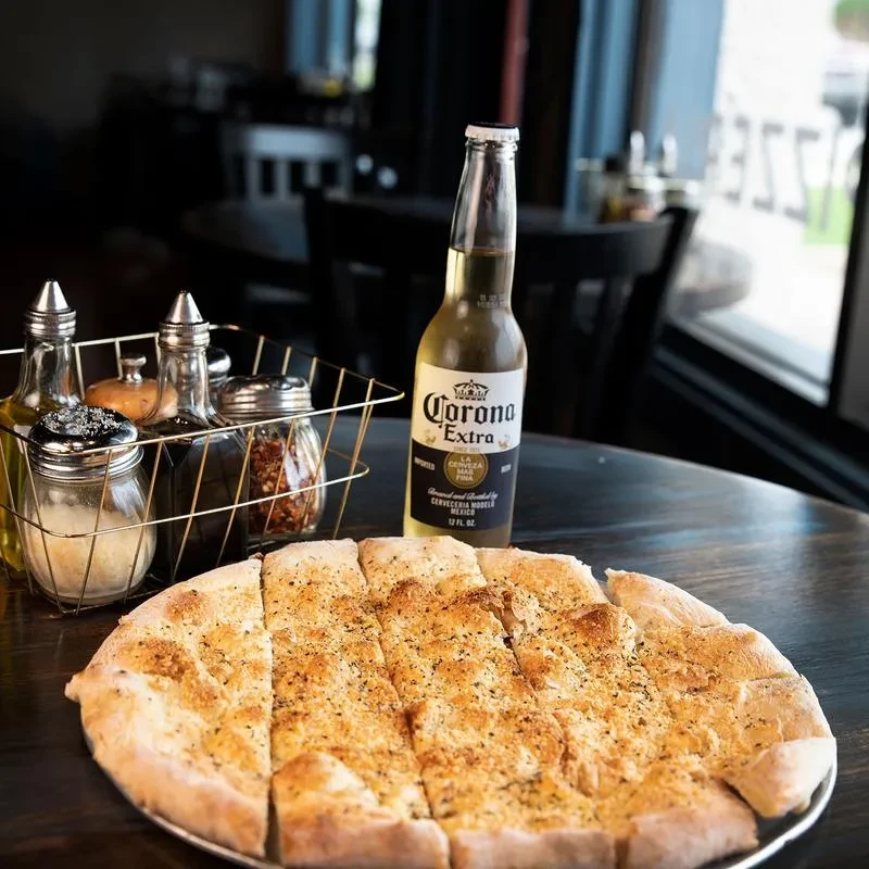 Flatbread, condiments, and Corona beer on a dark restaurant table.