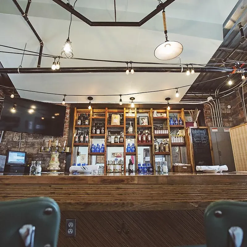 Bar back with liquor shelves under skylight and exposed pipes