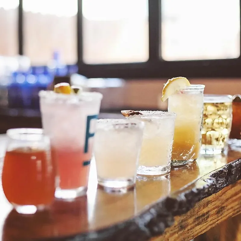 Row of cocktails and beers lined along wooden bar top
