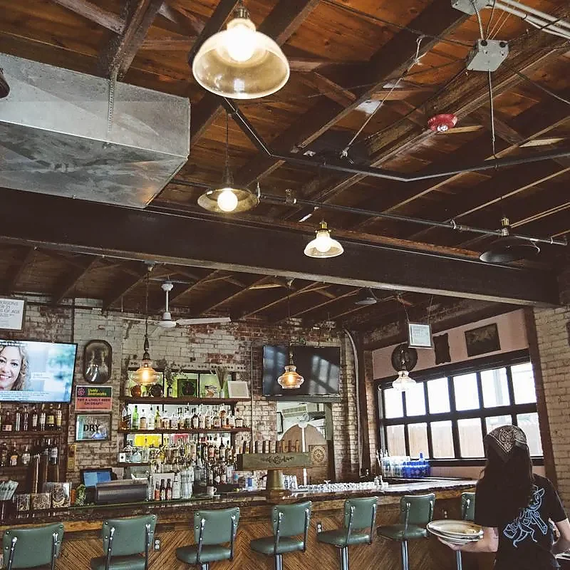 Interior bar with green stools, brick walls and wood ceiling