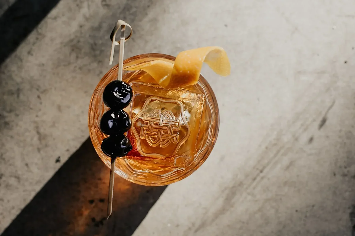 Old fashioned cocktail with cherries and orange peel, overhead view