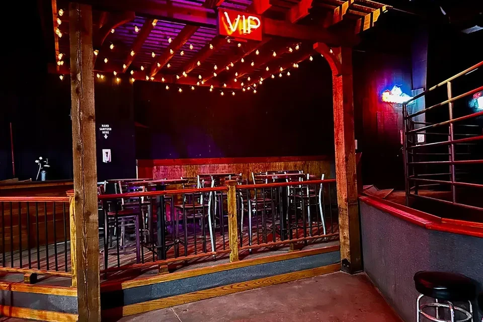 Red-purple lit lounge with a glowing pergola and VIP sign.