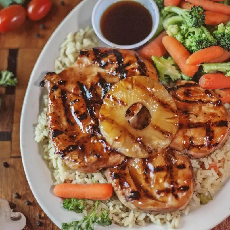 Grilled glazed chicken with pineapple, rice, broccoli, and carrots.