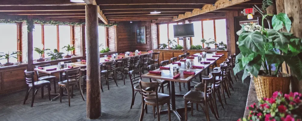 Empty lodge-like restaurant dining room with wooden tables and beams.