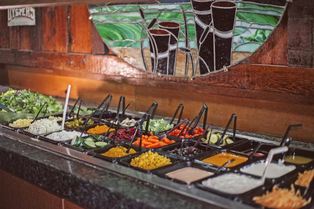 A well-stocked restaurant salad bar with fresh vegetables and toppings.