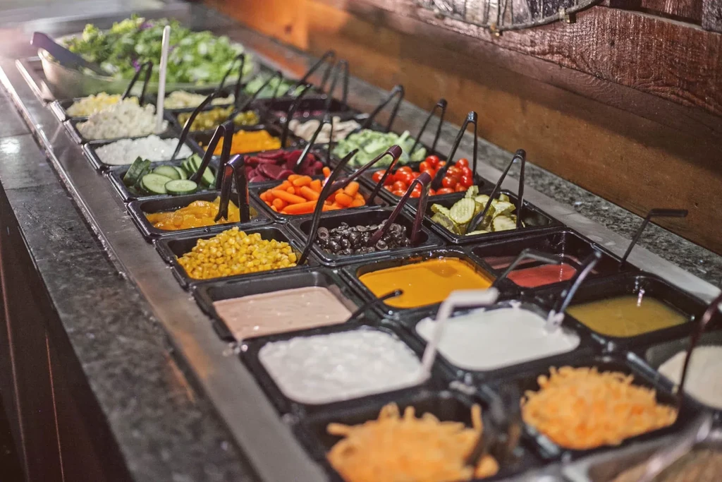 Well-stocked salad bar with a variety of fresh produce, cheeses, and dressings.
