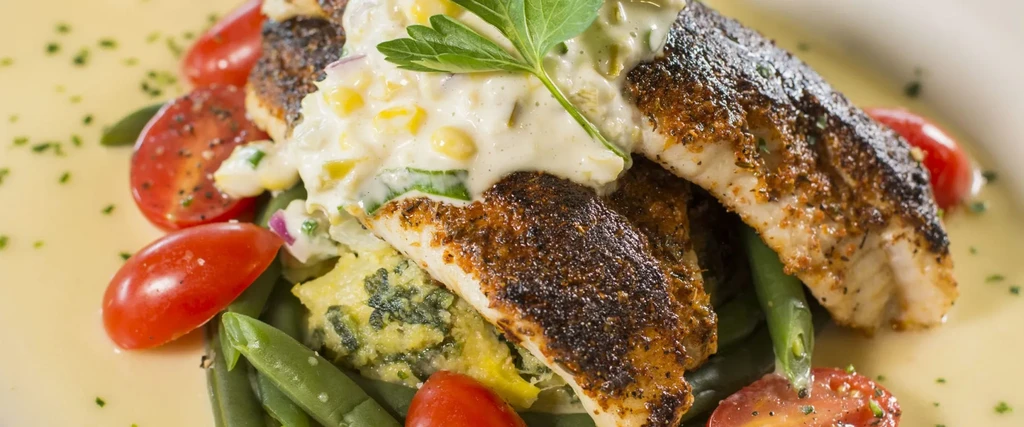 Pan-seared fish, creamy corn relish, green beans, vegetable mash, and tomatoes.