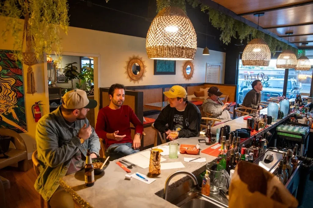 Patrons conversing and drinking at a well-stocked restaurant bar.