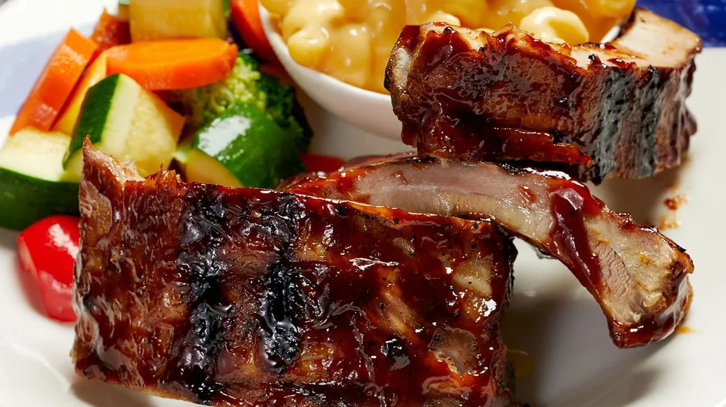 Glistening barbecued ribs with mixed vegetables and macaroni and cheese.