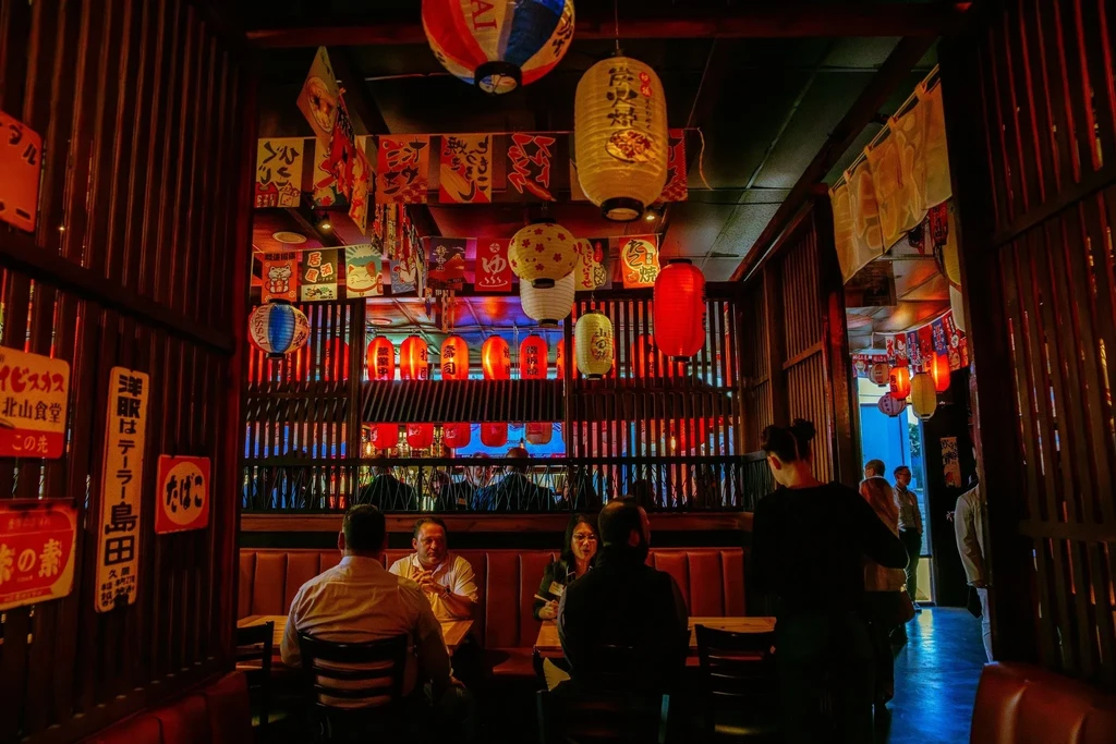 Japanese restaurant interior filled with colorful lanterns, banners, and diners.