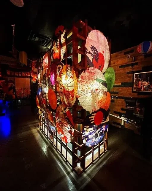 Vibrantly lit structure of traditional Asian parasols in a dim interior.