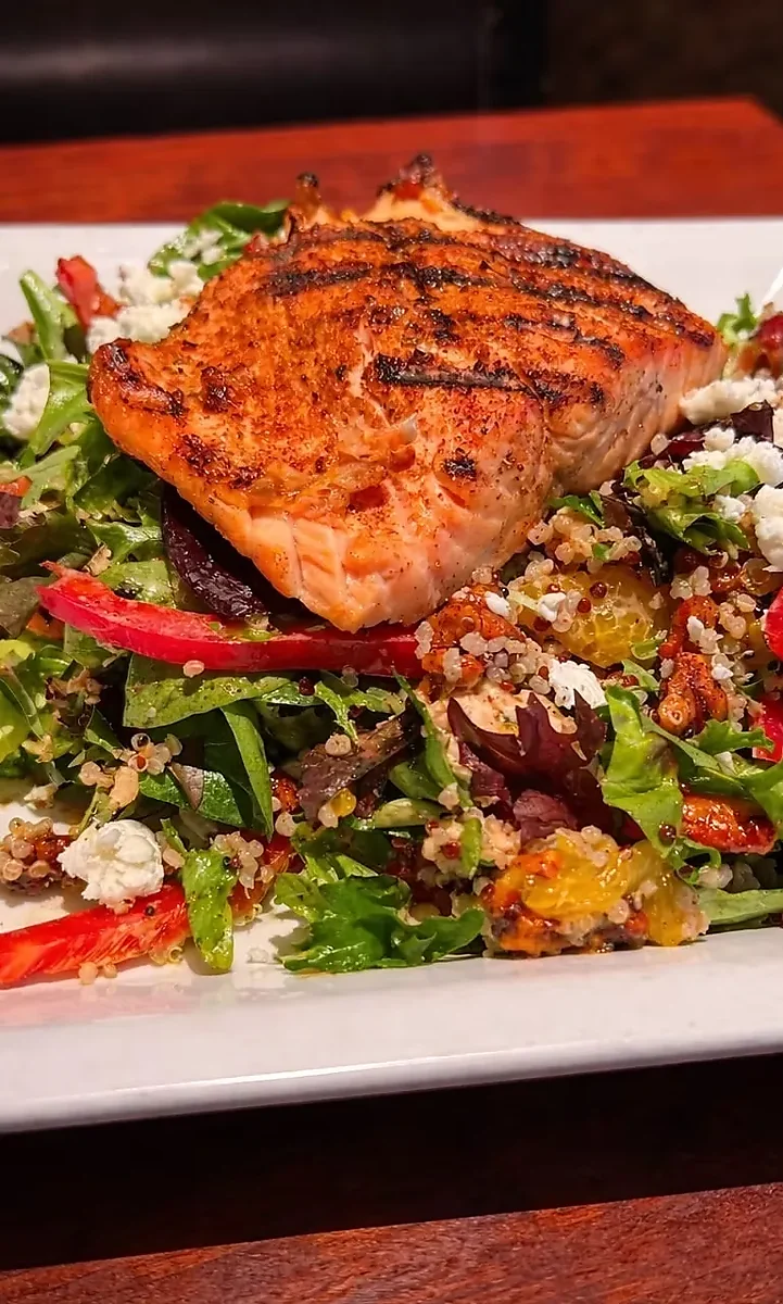 Grilled salmon fillet over quinoa salad with goat cheese and greens