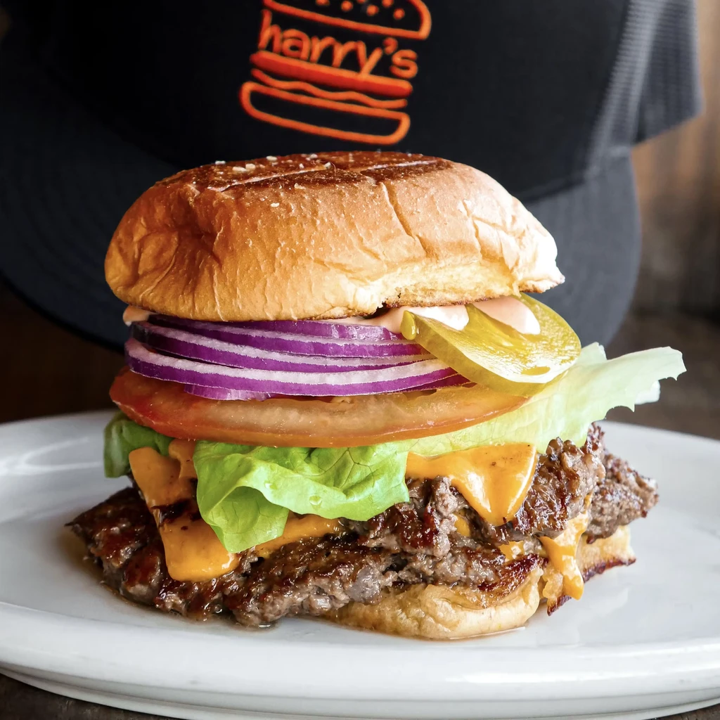 A double cheeseburger with lettuce, tomato, red onion, pickle, and sauce.