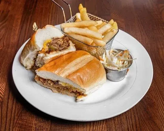 A pulled pork sandwich, fries, and coleslaw on a white plate.
