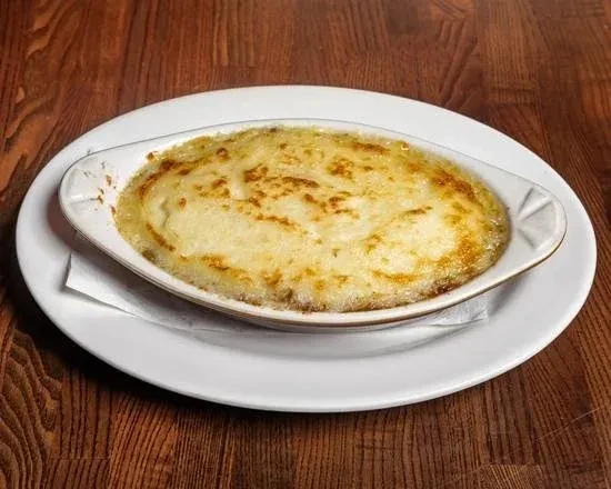 A white oval baking dish filled with gratin on a wooden table.