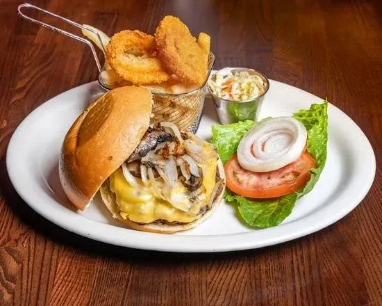 A cheesy mushroom burger with fries, onion rings, coleslaw, and fresh toppings.
