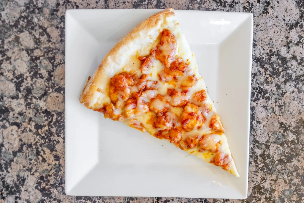 A slice of buffalo chicken pizza on a white square plate.