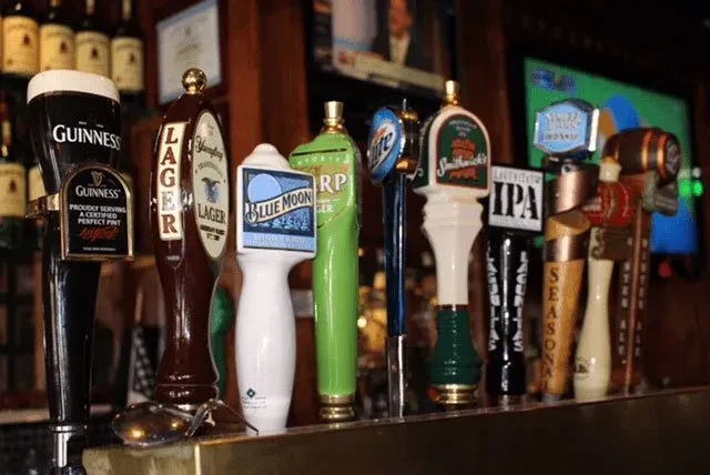 A row of various beer tap handles with brand names visible.