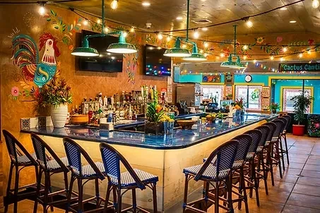 A colorful, empty bar with blue countertop and stools at Cactus Cantina.