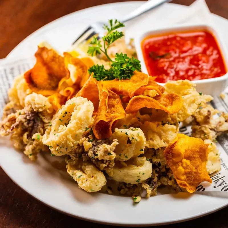 A plate of fried calamari, sweet potato chips, and marinara sauce.