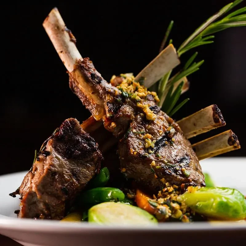 A rack of lamb, with bones exposed, on a white plate.