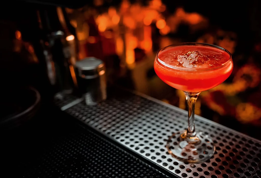 A red cocktail with crushed ice on a bar mat.