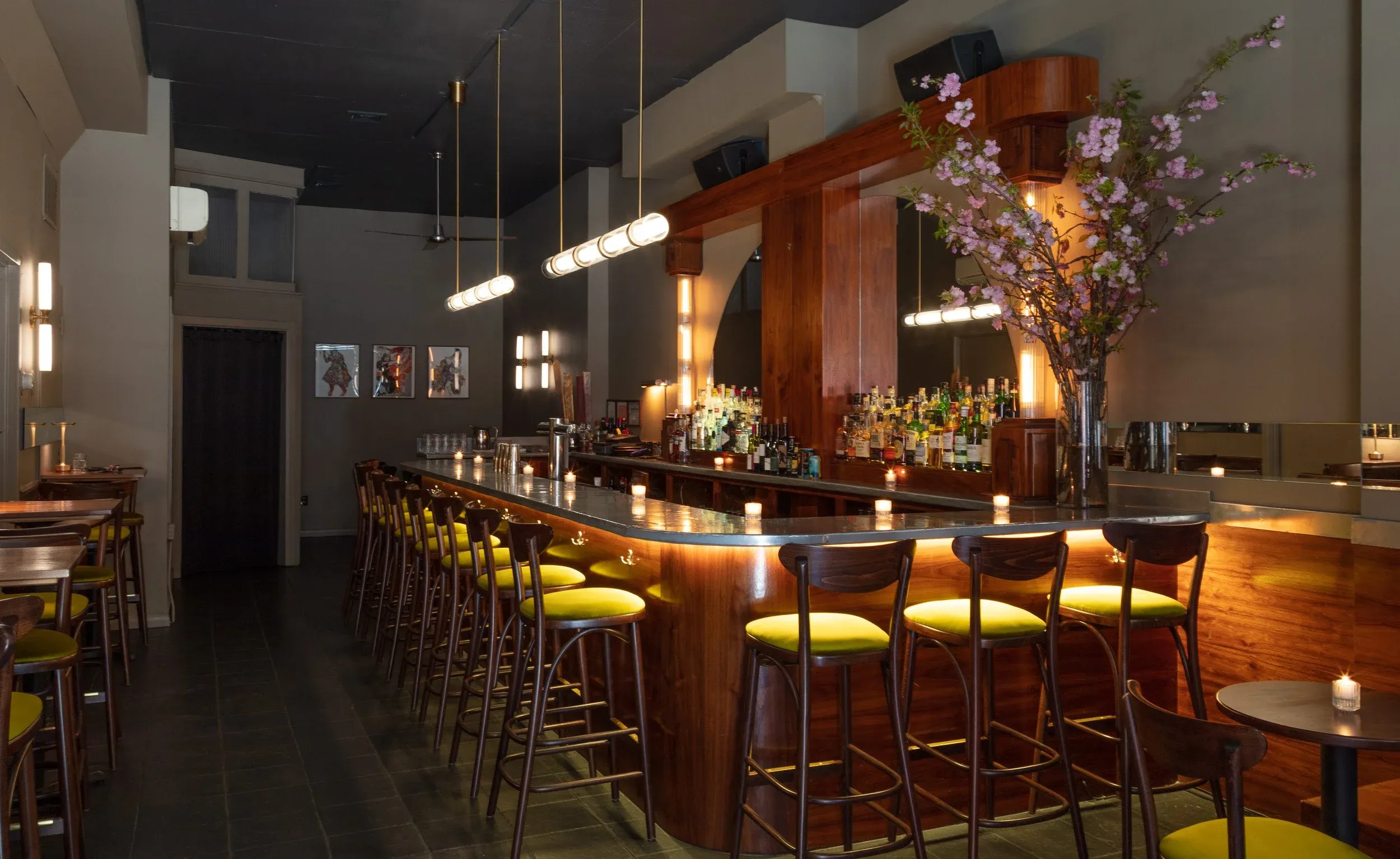 A modern bar with a wooden counter, chartreuse stools, and overhead lighting.