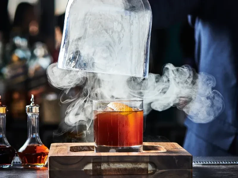 Smoked cocktail in a glass with an orange peel garnish.