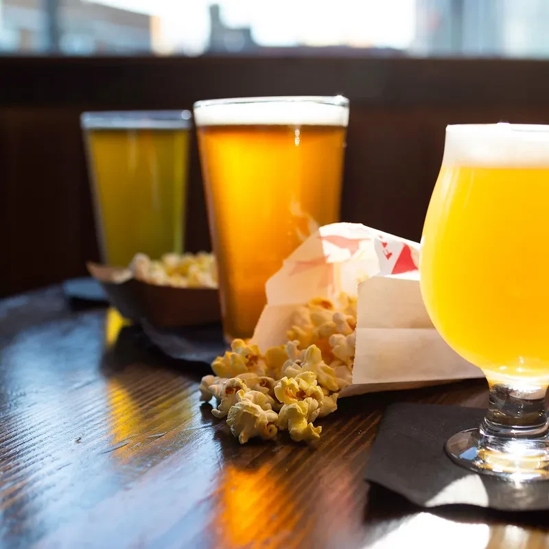 Popcorn and three glasses of beer on a wooden table.