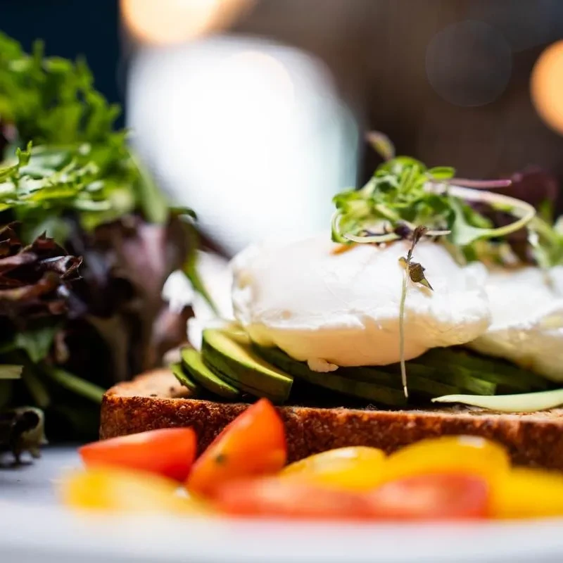 Avocado toast with poached eggs, cherry tomatoes, and microgreens.