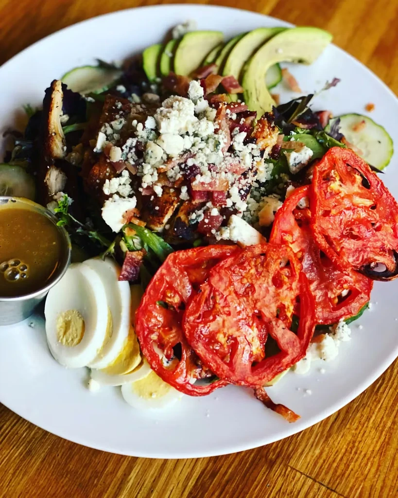 Chicken salad with avocado, bacon, tomatoes, eggs, and blue cheese.