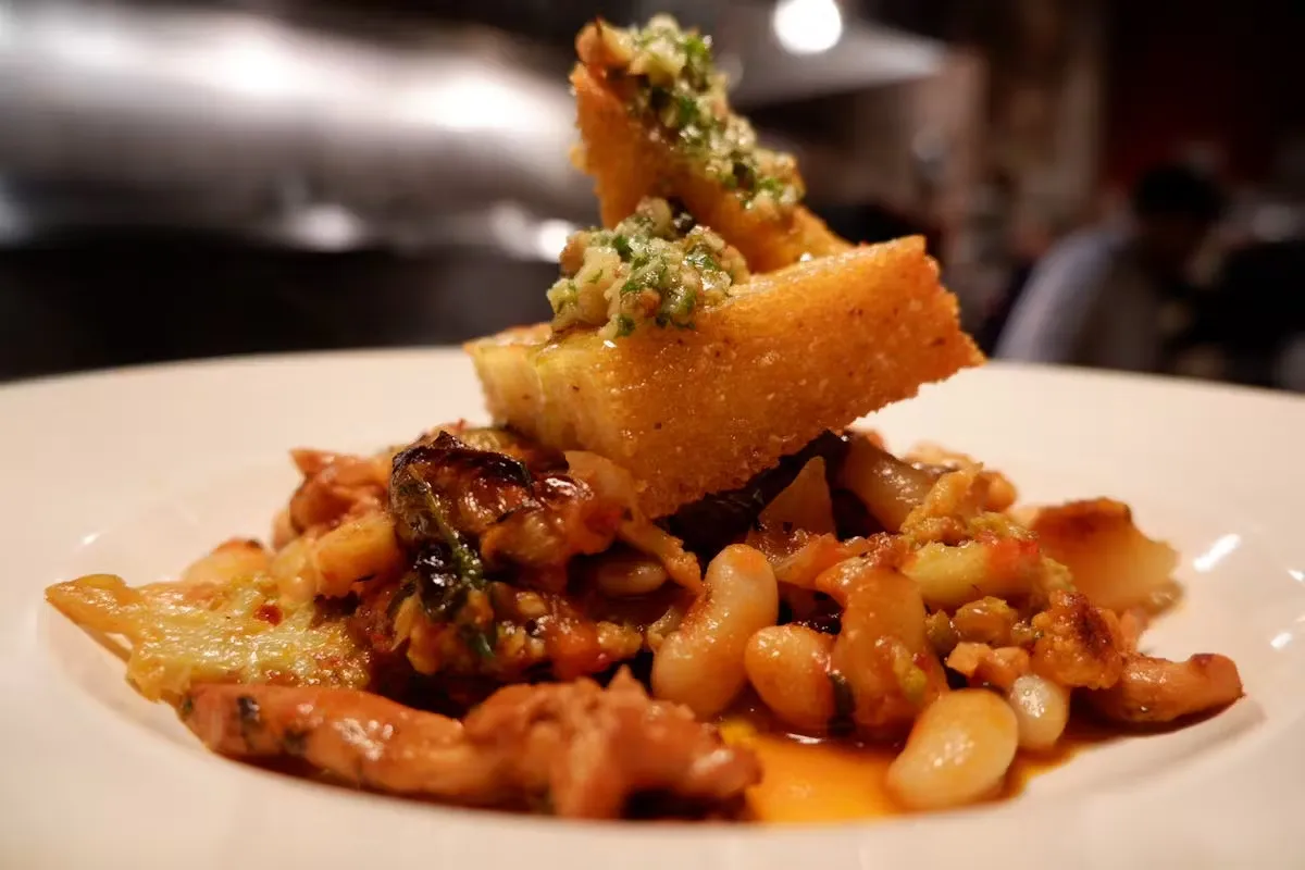 Savory dish with white beans and bread topped with green sauce.
