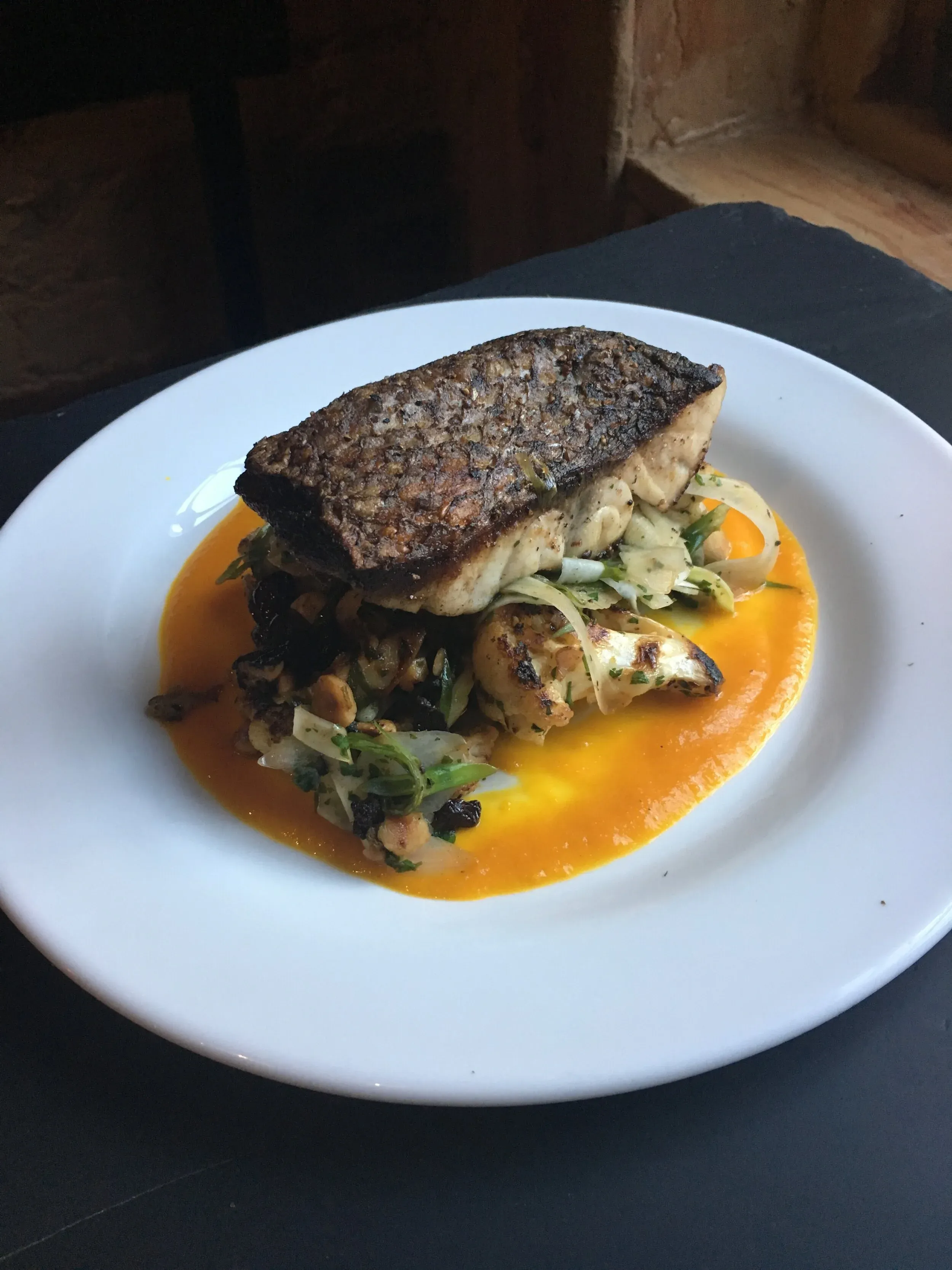 Seared fish fillet on vegetable medley with orange sauce.