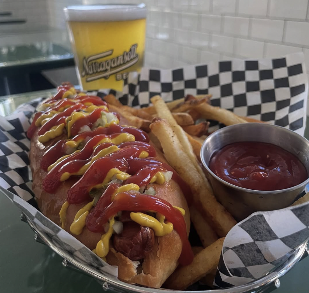 Hot dog with ketchup and mustard, fries, and a beer.