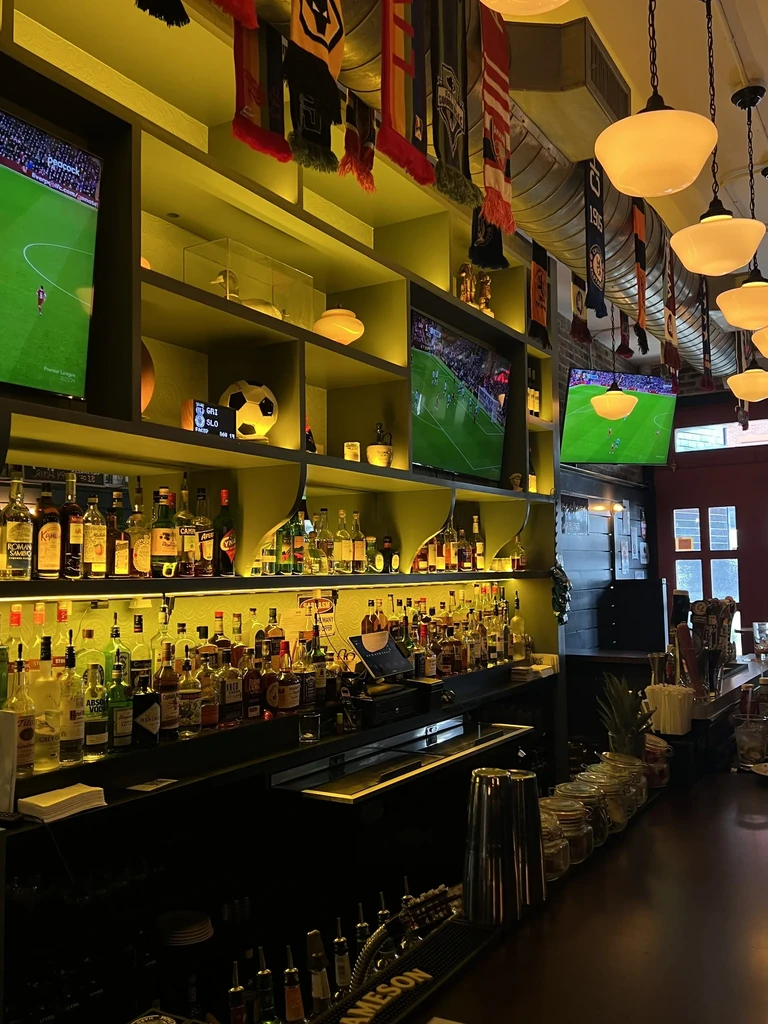 A bar with many liquor bottles, TV screens, and sports memorabilia.