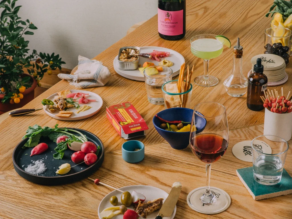 An overhead view of a wooden table set with drinks and appetizers.