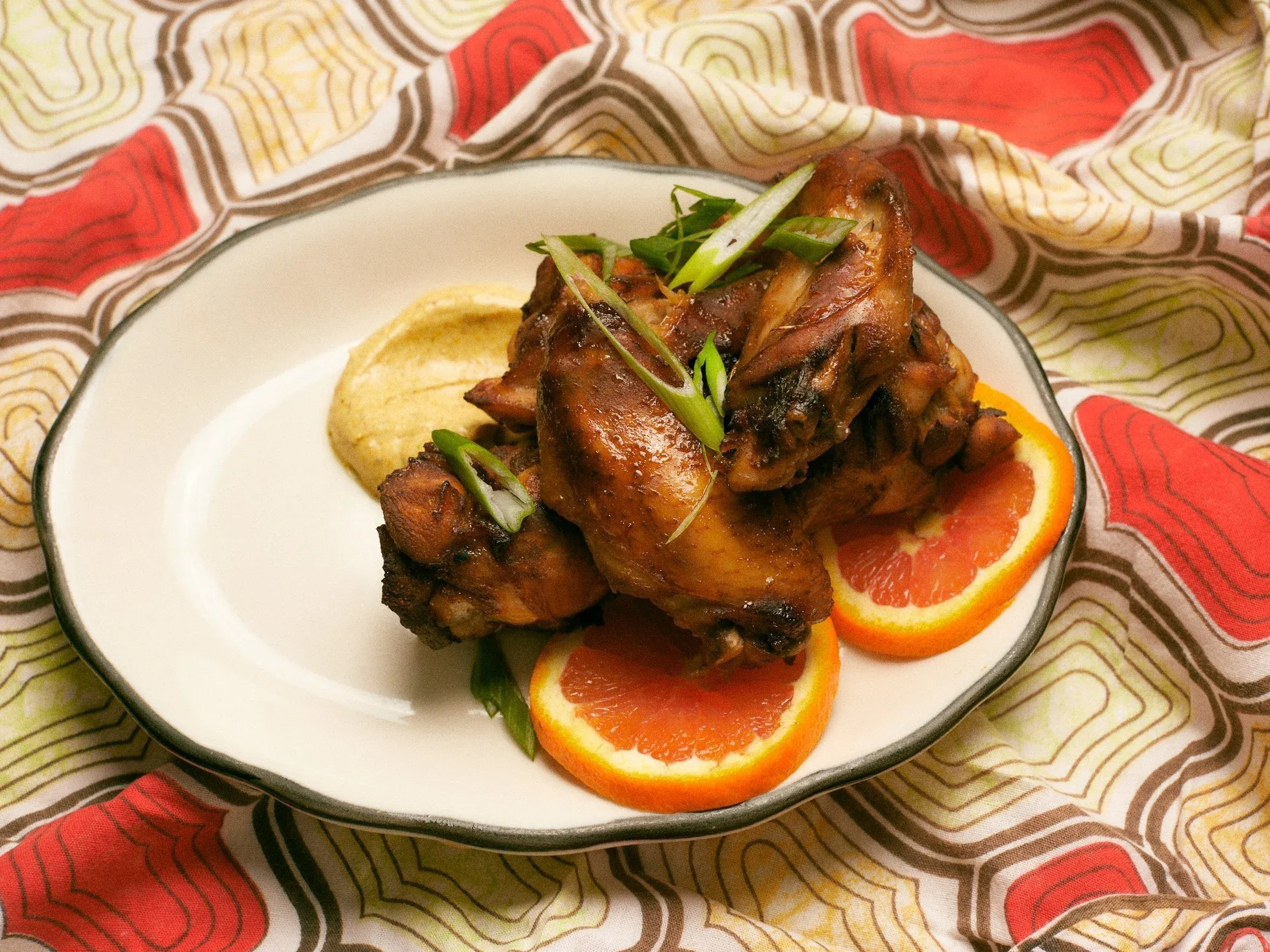 Baked chicken with orange slices and a creamy yellow side on a white plate.