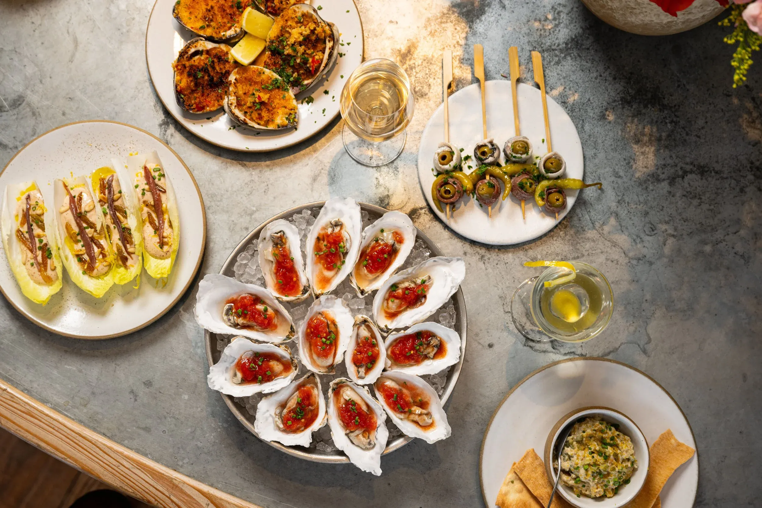 An overhead view of multiple seafood appetizers and drinks on a table.