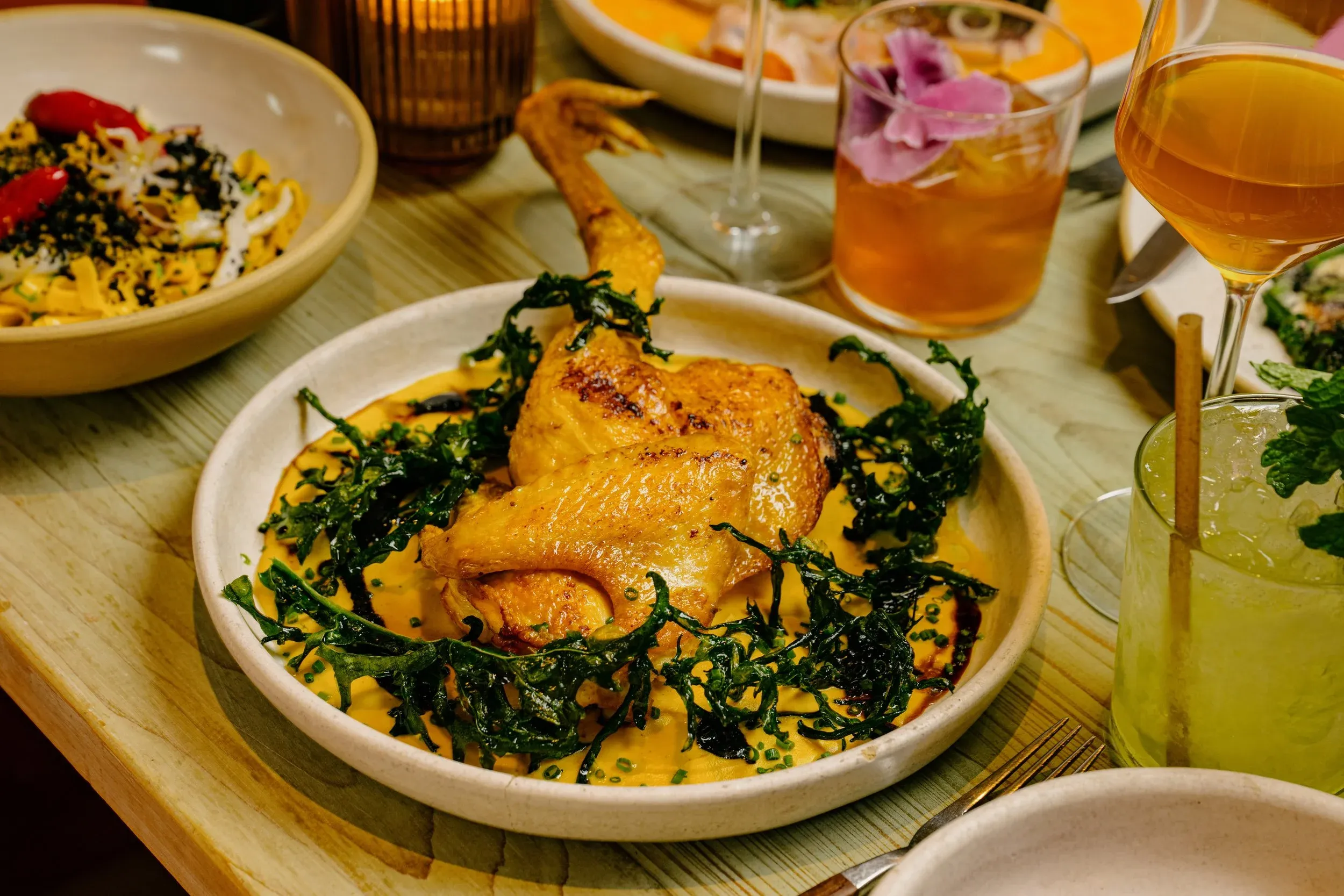 Crispy chicken leg and thigh in a yellow sauce with green garnish.