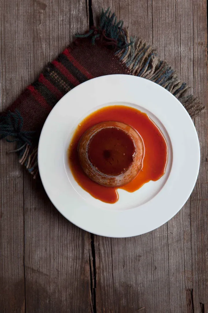 Creme caramel dessert with sauce on a white plate.