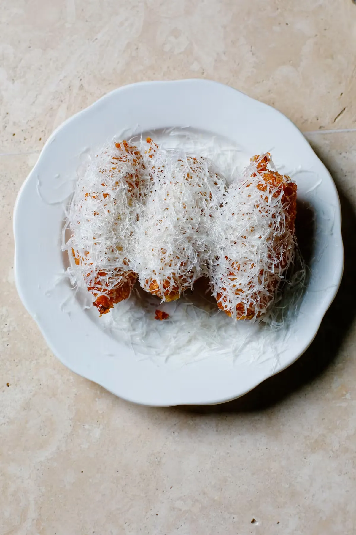 Three fried pastries covered in shredded coconut on a white plate.