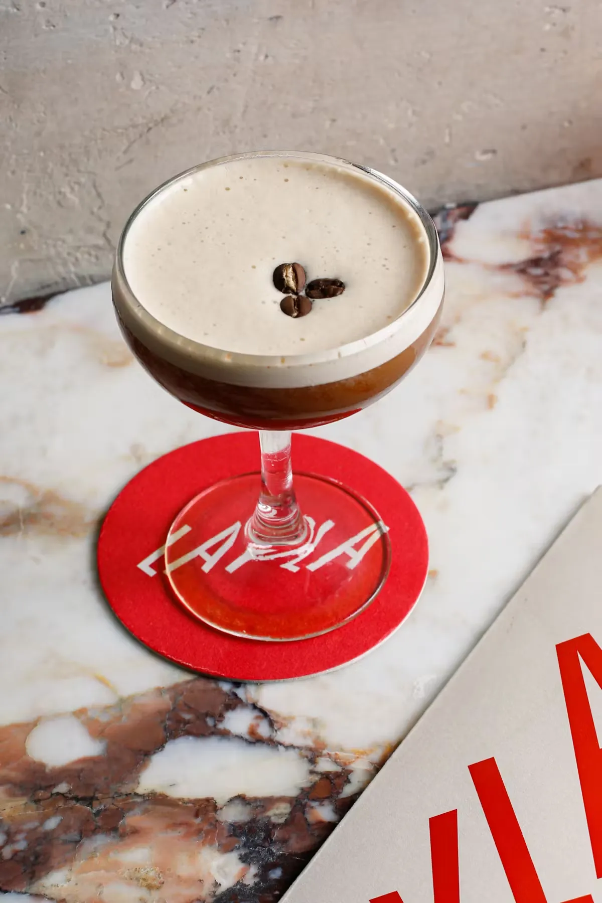Espresso martini in a coupe glass with coffee bean garnish on marble.