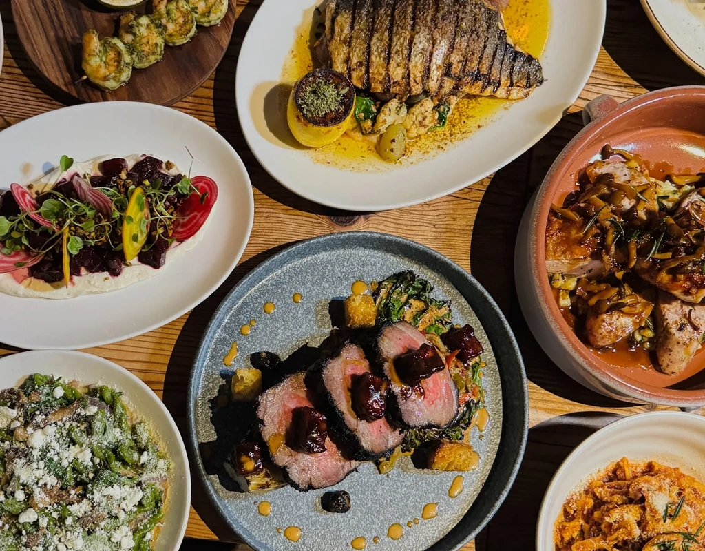 An overhead shot of several restaurant dishes on a wooden table.