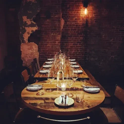 Long wooden dining table set in a brick room.