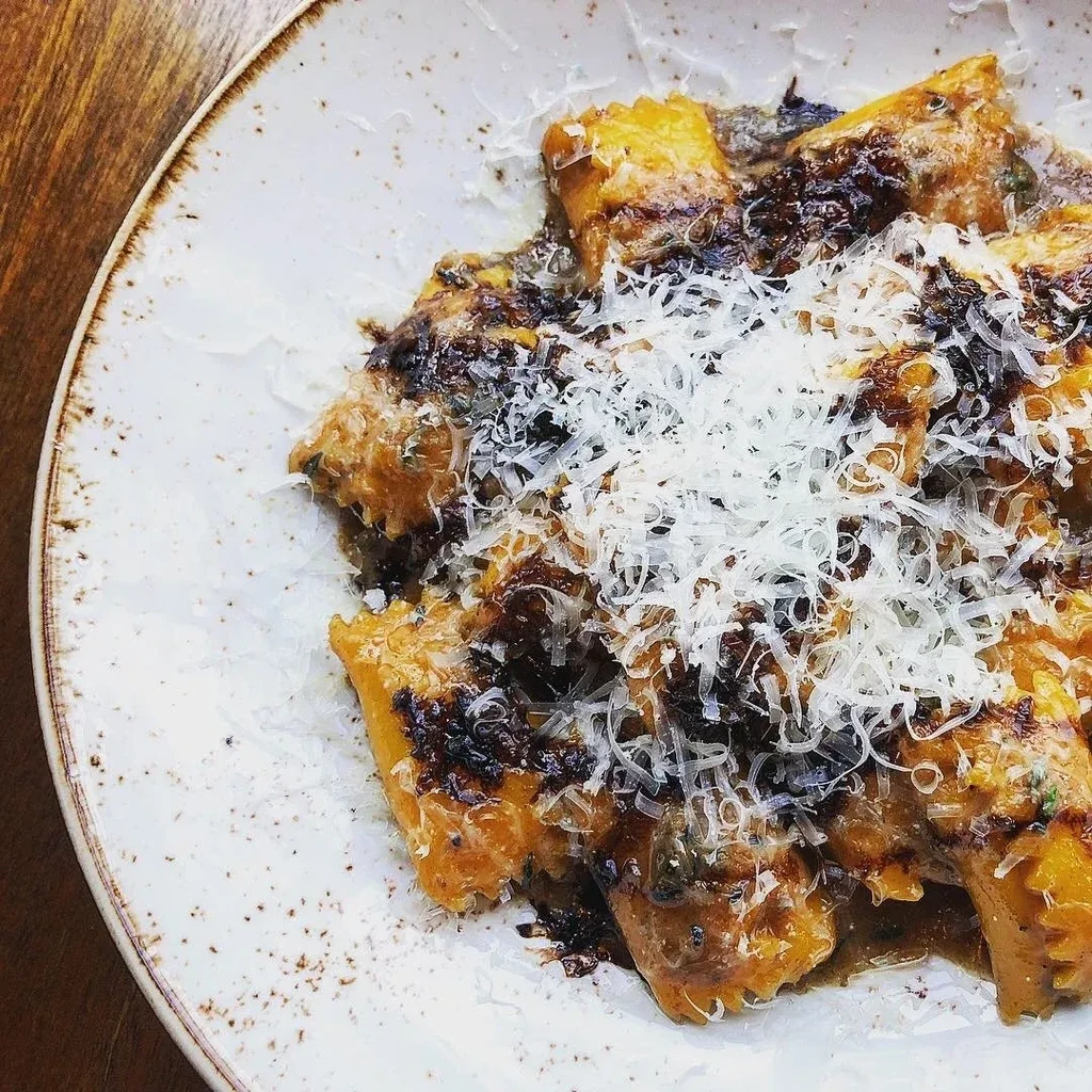Plate of pumpkin gnocchi with mushroom sauce and shredded parmesan cheese.